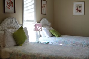 Un dormitorio con dos camas, ropa de cama blanca y una lámpara de noche.