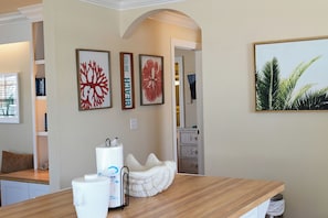 Una habitación con un mostrador de madera, un adorno blanco y obras de arte enmarcadas en la pared.