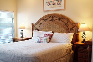 A neatly made bed with a headboard, two bedside lamps, and a framed picture above the bed.