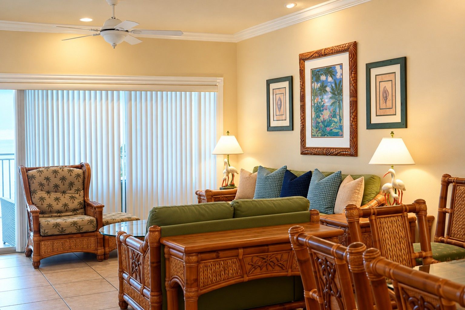 A room with a bed, two armchairs, a wooden table, and a ceiling fan.