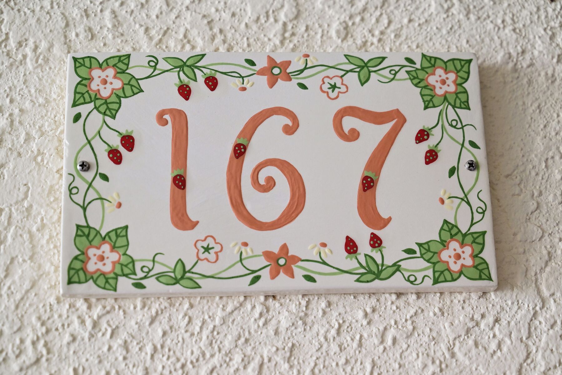 Uma placa decorativa com o número 167, rodeada por motivos florais.