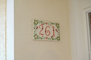 A wall-mounted sign with the number '261' surrounded by floral and berry designs.