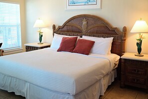 A large bed with a wooden headboard, two bedside lamps, and a framed picture on the wall.
