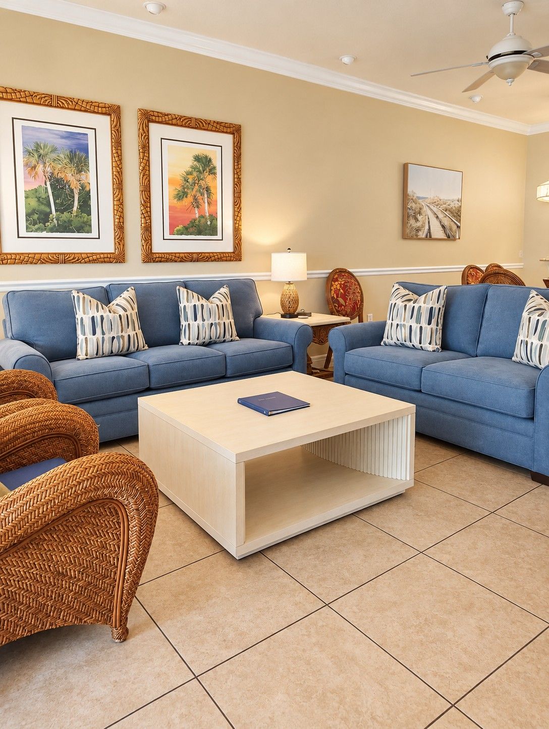 A living room with two sofas, a coffee table, wicker chairs, and framed artwork on the walls.
