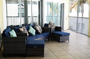 Un balcón con un sofá modular y dos sillones, con vistas al exterior.