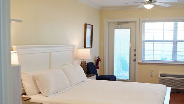 Quarto com cama, luminárias de cabeceira, janela e ventilador de teto.