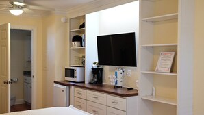 A hotel room with a bed, a flat-screen TV mounted on the wall, a microwave, a coffee maker, and a small refrigerator. - Hotel Room Convenient Ground-Floor Room Steps from the Beach (Bradenton Beach)