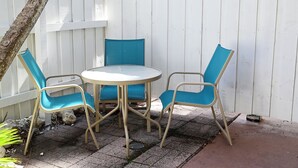 A patio with a round table and four chairs, a white fence, and a tree. - Hotel Room Convenient Ground-Floor Room Steps from the Beach (Bradenton Beach)