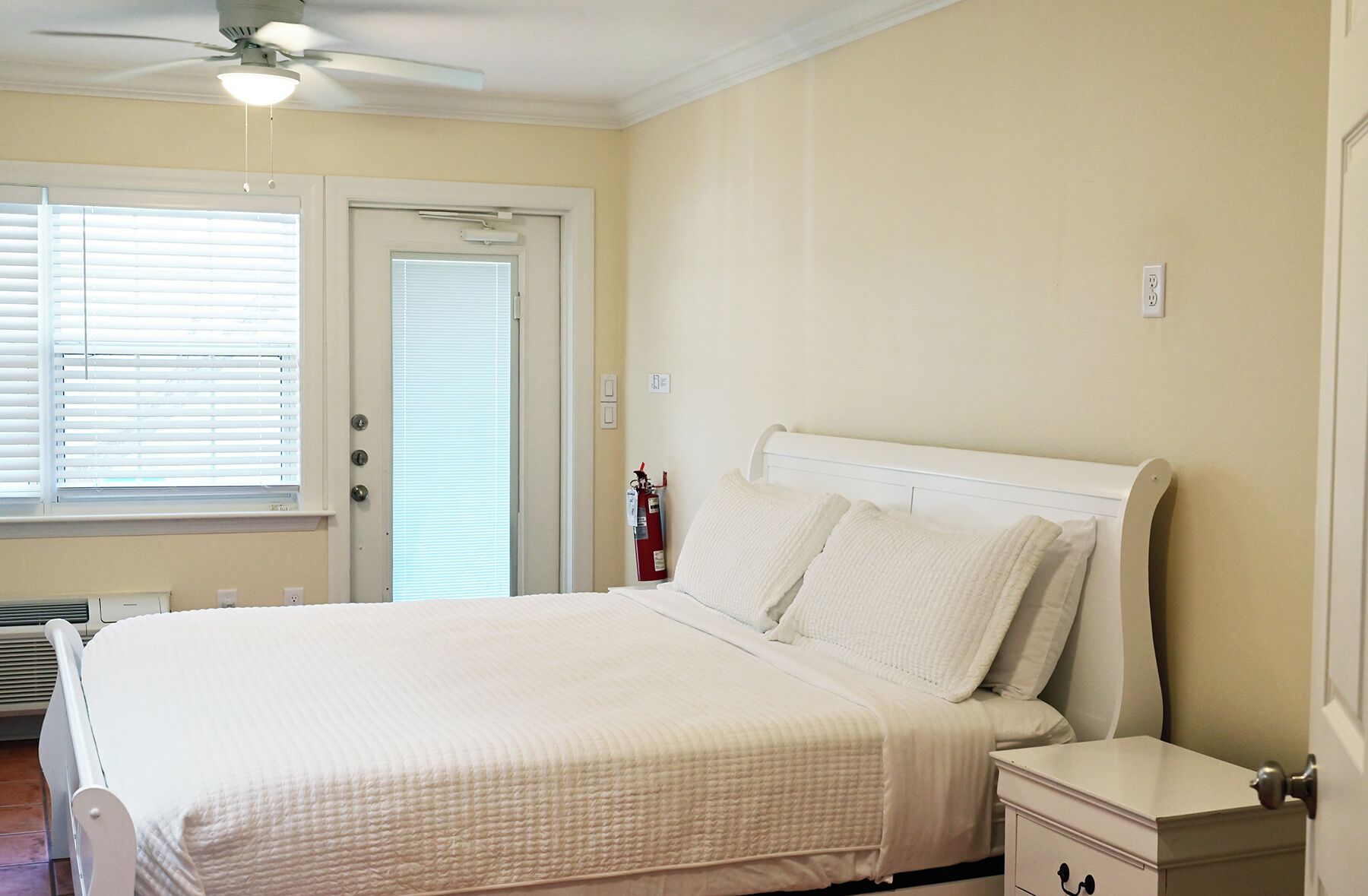 Un dormitorio con cama, mesita de noche y ventilador de techo.