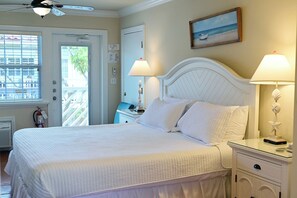 Una habitación de hotel con cama, lámparas de noche, una mesita de noche, una ventana con persianas y un cuadro en la pared.