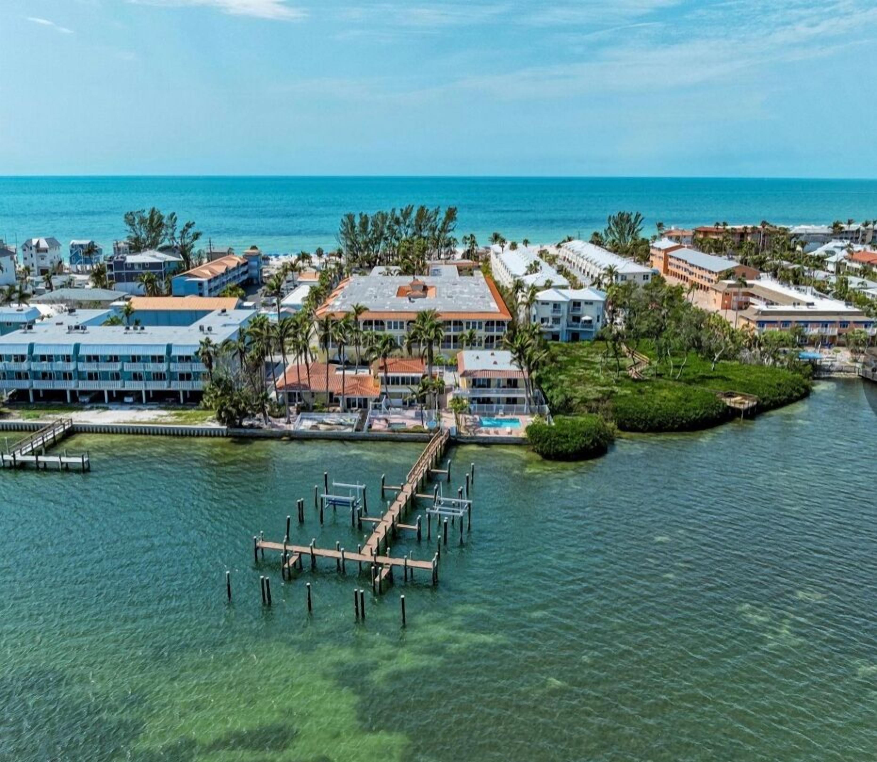 A coastal resort with multiple buildings, a dock, and clear blue water.