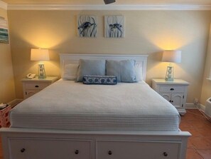Une chambre à coucher avec un grand lit, deux tables de chevet et des lampes fixées au mur.
