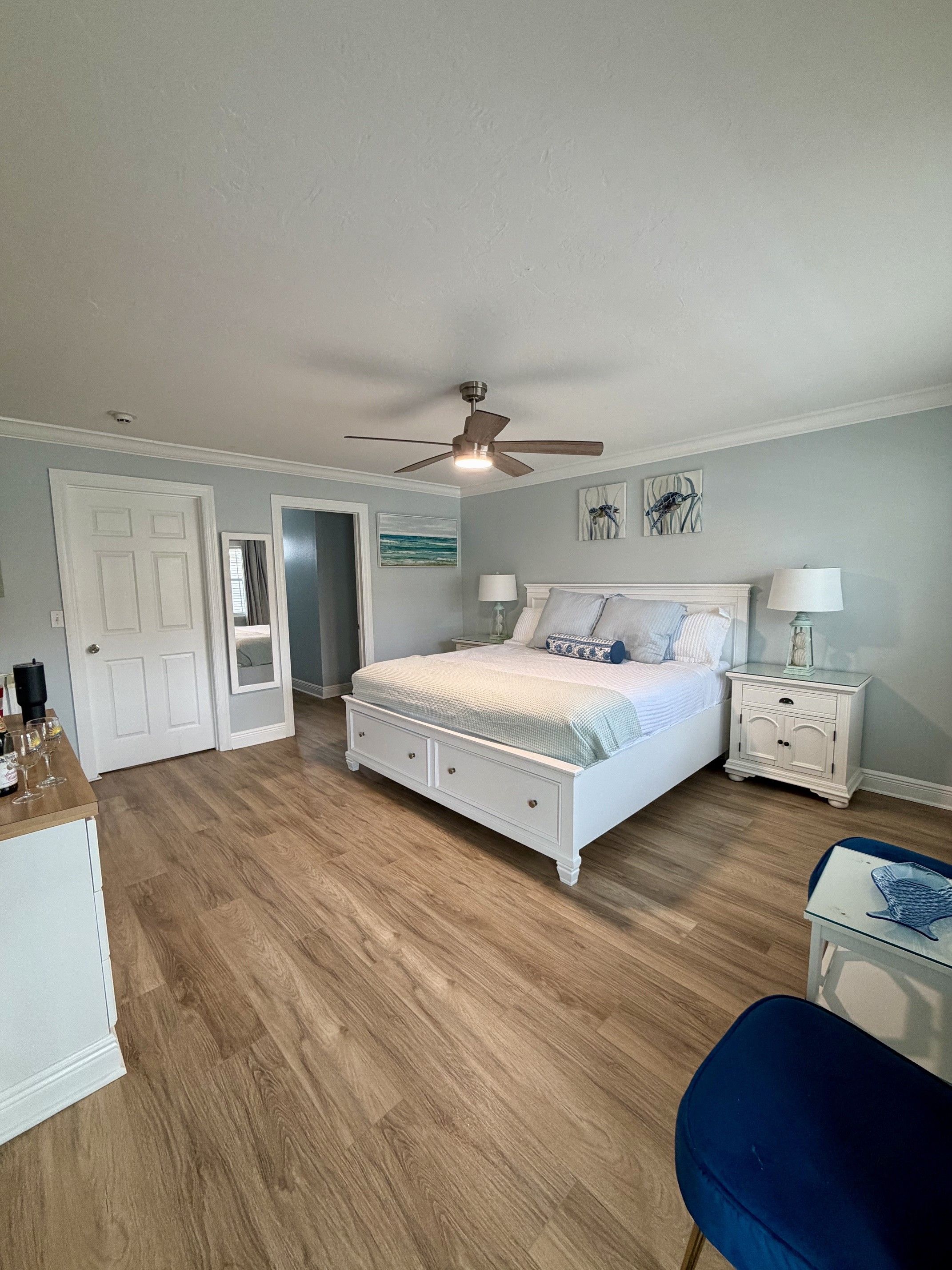 A bedroom with a bed, a ceiling fan, a nightstand, a dresser, and a chair.
