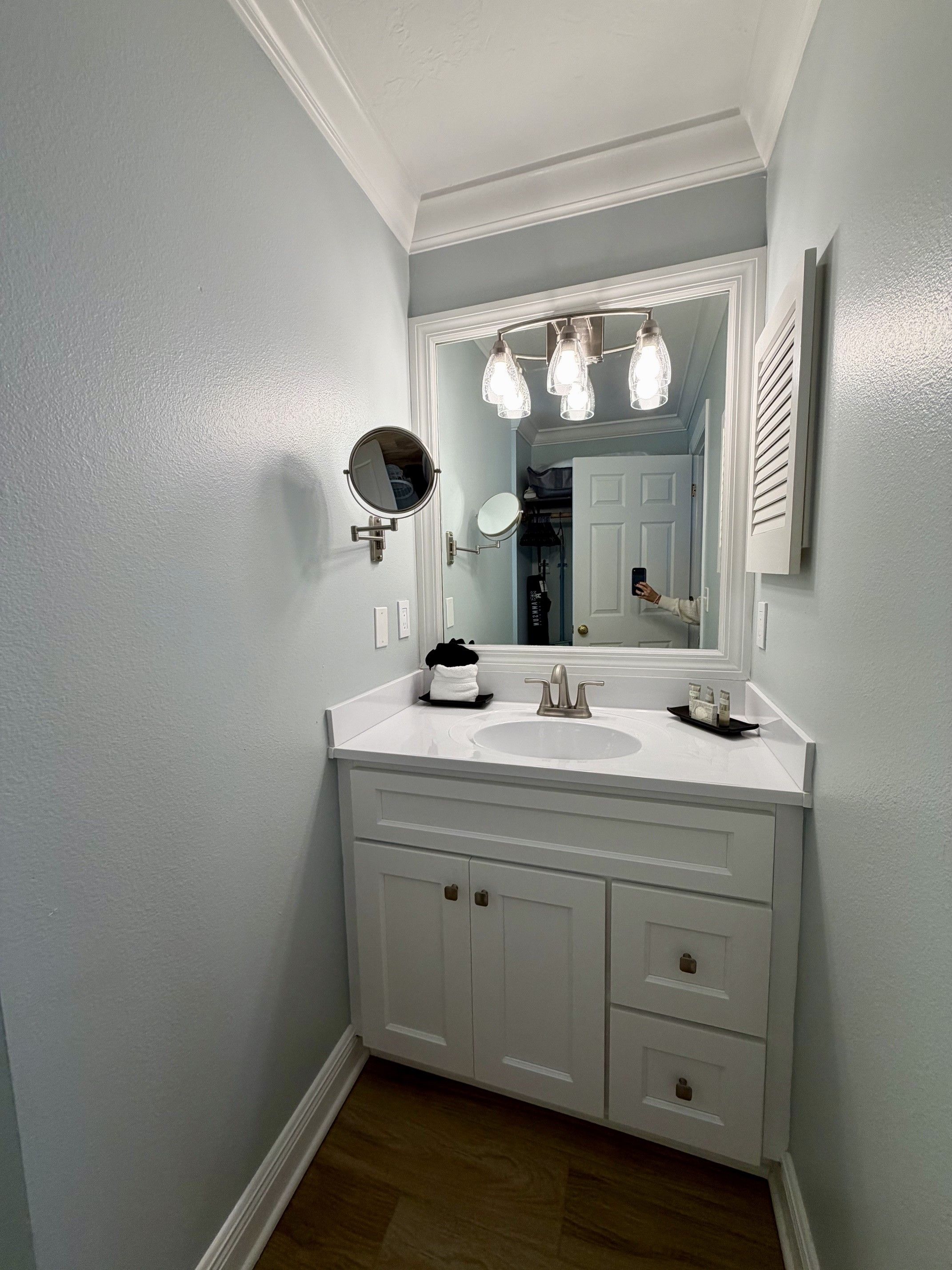 A bathroom with a white vanity, a round mirror, and a light fixture above the sink.