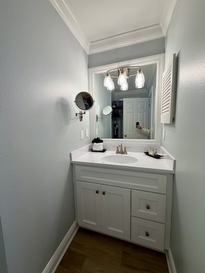A bathroom with a white vanity, a round mirror, and a light fixture above the sink. - 248B: Anna Maria Island , King Room, Steps from the beach (Bradenton Beach)