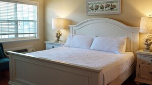 A bedroom with a bed, two bedside tables, a window with blinds, and a wall-mounted picture. - Bright Second-Floor Studio Near the Beach (Bradenton Beach)
