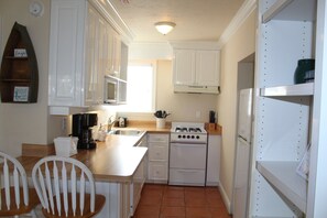 A compact kitchen with white cabinets, a stove, a sink, and a coffee maker. - Bright Second-Floor Studio Near the Beach (Bradenton Beach)