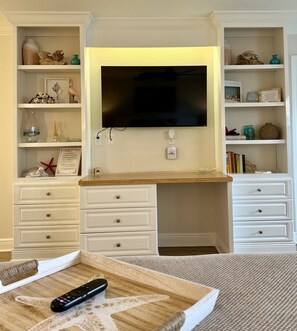 A living room with a flat-screen TV mounted on the wall, a wooden coffee table, and white furniture. - 248A: Anna Maria Island, King Studio, Steps from the Beach. (Bradenton Beach)