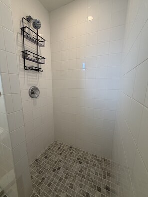 A shower with white tiles, a metal rack, and a showerhead. - 248A: Anna Maria Island, King Studio, Steps from the Beach. (Bradenton Beach)