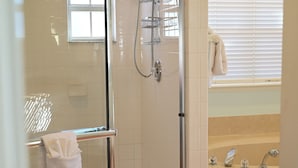 Un baño con ducha envuelta en cristal, bañera y retrete.