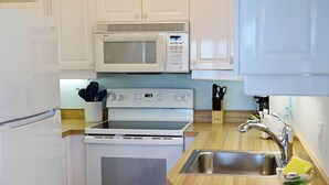 Una cocina con electrodomésticos blancos, incluyendo un microondas, horno y refrigerador.