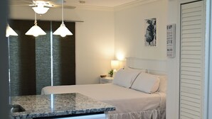 A hotel room with a bed, a nightstand, a lamp, a window with curtains, and a wall with a motivational poster.