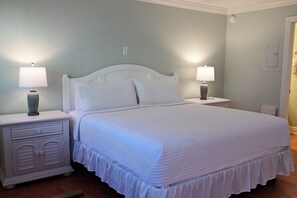 A neatly made bed with a white headboard and footboard, flanked by two bedside tables with lamps.