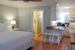 A bedroom with a bed, bedside lamp, and a bathroom with a shower and toilet.