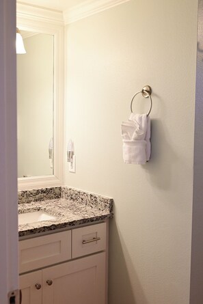 A bathroom with a granite countertop, a sink, a towel rack, and a mirror.