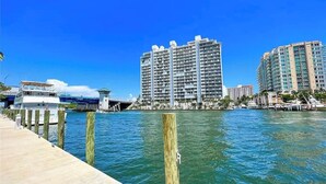 A waterfront view with high-rise buildings, a dock, and a bridge.
