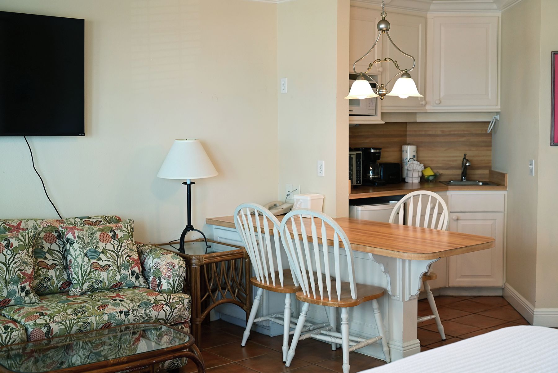 Un espacio habitable compacto con sofá, una mesa de comedor con sillas, una lámpara y una kitchenette.
