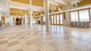 A spacious hall with high ceilings, large windows, and a checkered floor.