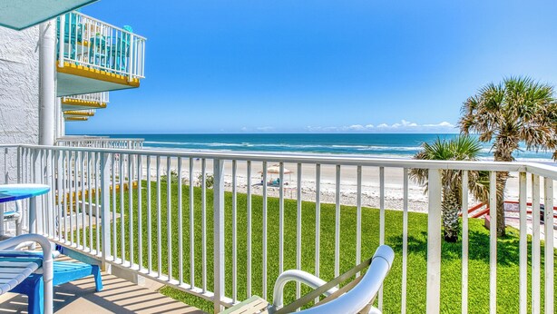 A balcony with a view of the beach, a pool table, and a palm tree. - Oceanfront Corner Condo with Ocean and Pool Views Private Balcony Car Free Beach (New Smyrna Beach)