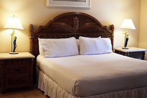 A neatly made bed with a wooden headboard, two bedside tables with lamps, and a framed picture on the wall.