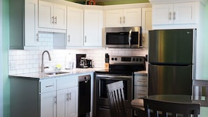 A modern kitchen with white cabinets, a stainless steel refrigerator, a microwave, a coffee maker, and a dishwasher. - Waterfront Views · One-Bedroom Bayfront Escape (Bradenton Beach)
