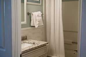 A bathroom with a white sink, a towel hanging on a rack, and a shower curtain.