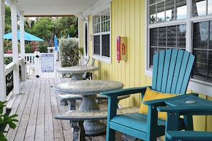 A covered outdoor area with a table and chairs, a sign with pool rules, and a fire extinguisher on the wall.