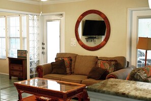 A living room with a sofa, a television mounted on the wall, and a glass coffee table.