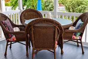 A wicker table and chairs set on a porch with a view of greenery. - Room to Relax · Two-Bedroom Stay on Gulf Drive (Bradenton Beach)