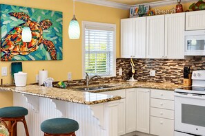A kitchen with white cabinets, a granite countertop, a sink, and a stove. - Room to Relax · Two-Bedroom Stay on Gulf Drive (Bradenton Beach)