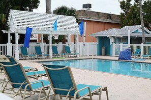 Zona de piscina con sillones de descanso y un área de estar techada.