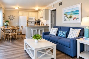 A compact living space with a kitchenette, a dining area, and a seating area with a blue sofa and cushions.