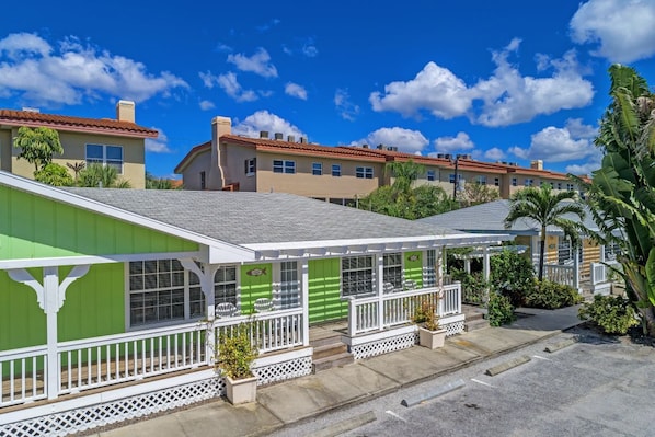 A residential building with a green facade, white railings, and a covered porch area. - Relaxed Luxury · Refined North-Side 1 bedroom (Bradenton Beach)