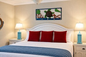 A bedroom with a bed, two nightstands, two lamps, a headboard, and a wall art piece. - Relaxed Luxury · Refined North-Side 1 bedroom (Bradenton Beach)