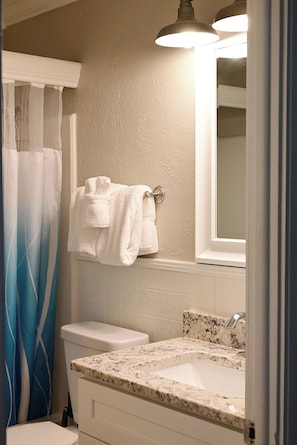 A bathroom with a toilet, sink, and a towel rack with towels.