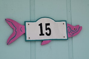 Letrero de placa con el número 15, colocado sobre una pared color aguamarina.