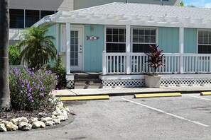 A building with a light blue exterior, a white porch, and a parking area with yellow lines.