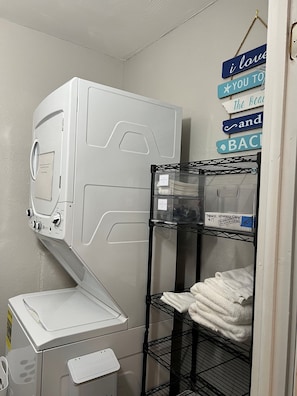 Un espace buanderie équipé d’un lave-linge, d’un sèche-linge et d’étagères pour ranger les serviettes pliées.