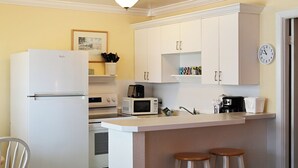 Une cuisine compacte équipée d’un réfrigérateur, d’un four à micro-ondes, d’une machine à café et d’une horloge murale.
