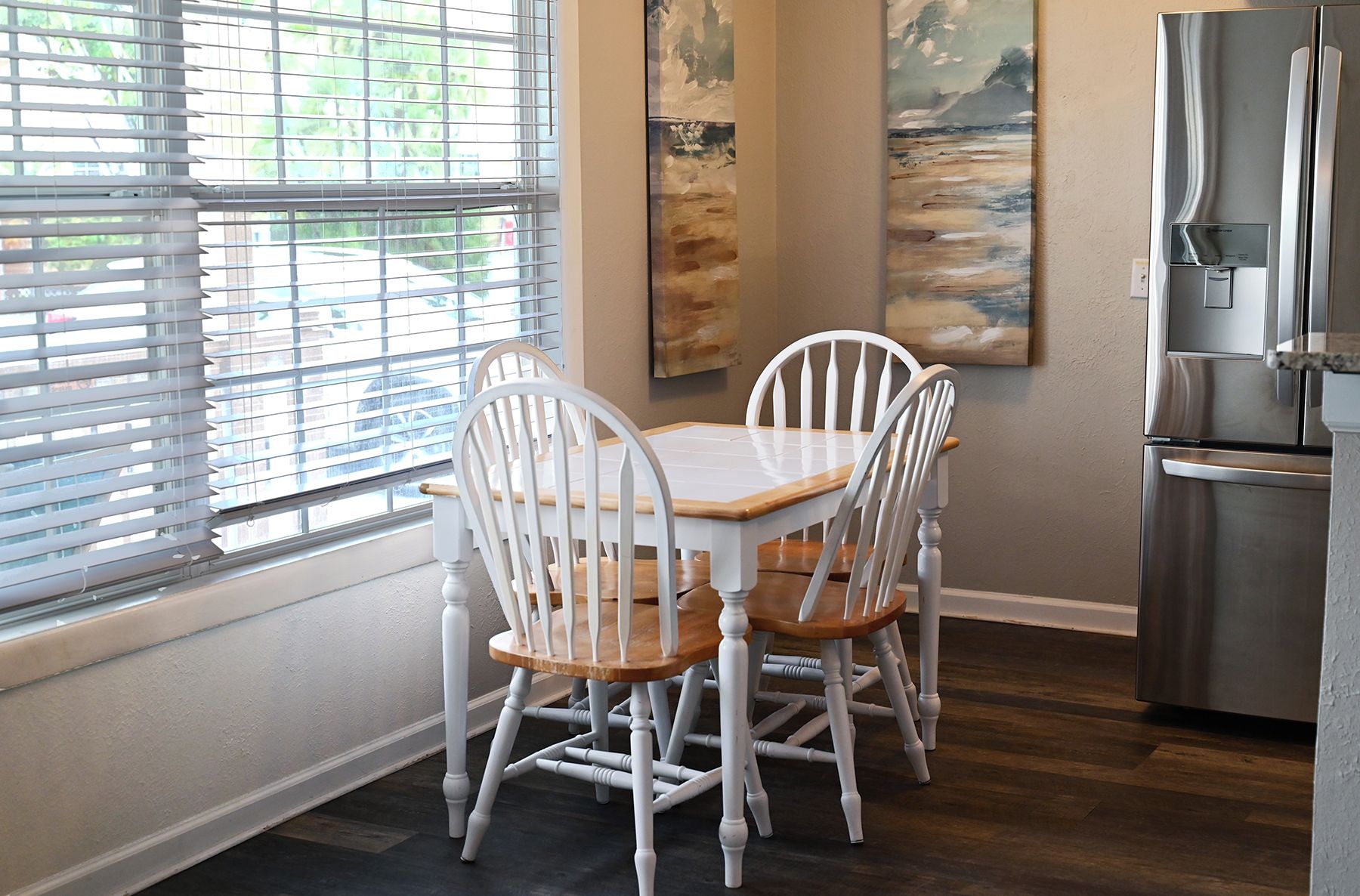 A dining area with a table and chairs, a refrigerator, and artwork on the walls.